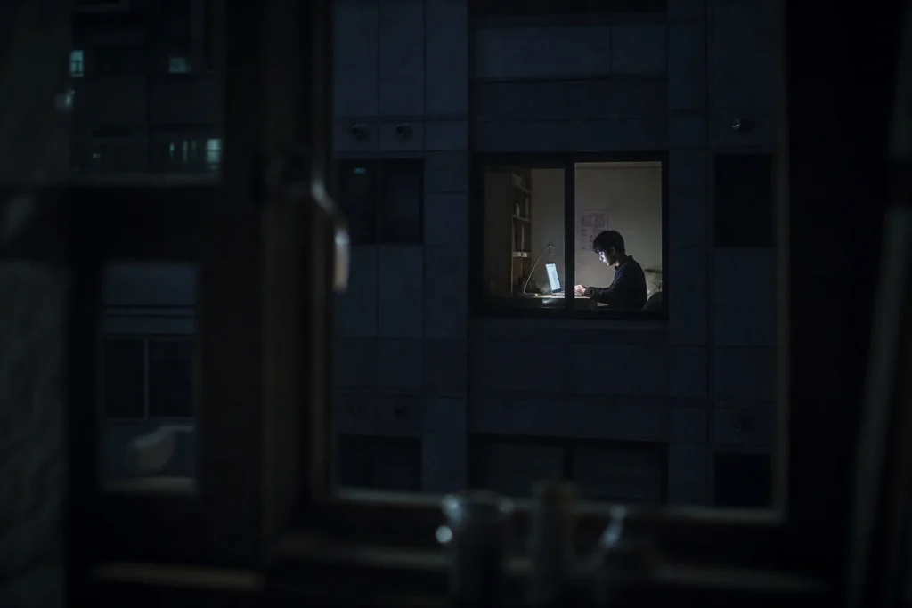 건너편 건물 창문 너머로 보이는 밤샘 코딩 중인 학생